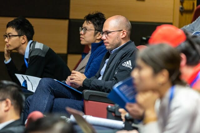 Man sitting on chair listening with other young people to a lecture at a university or college